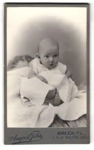 Fotografie August Töke, Bruck a. L., Lagerstrasse 3, Kleinkind im weissen Gewand mit aufmerksamem Blick