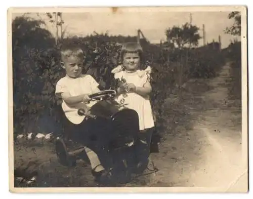 Fotografie unbekannter Fotograf und Ort, zwei kleine Kinder mit Tretauto / Seifenkiste, Kühlerfigur N