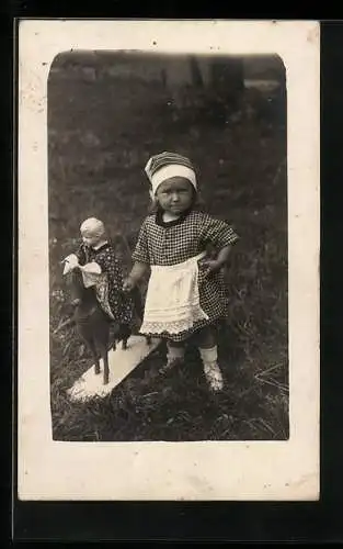 Foto-AK Kleines Mädchen mit Puppe auf einem Pferdchen
