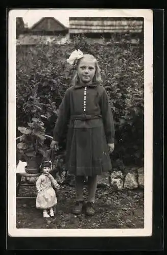 Foto-AK Mädchen mit Haarschleife und Puppe in einem Garten