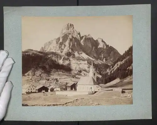 Fotografie unbekannter Fotograf, Ansicht Corvara, Blick auf den Ort mit Kirche und dem Sassongher im Hintergrund