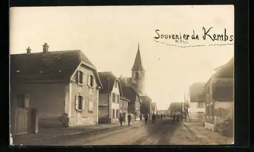 Foto-AK Kembs /Haut-Rhin, Strassenpartie mit Blick zur Kirche