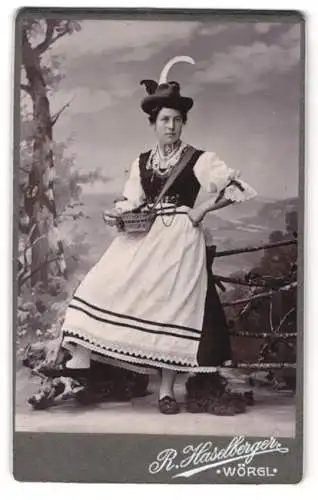 Fotografie R. Haselberger, Wörgl, junge Dame im Trachtenkleid mit Federhut und Körbchen