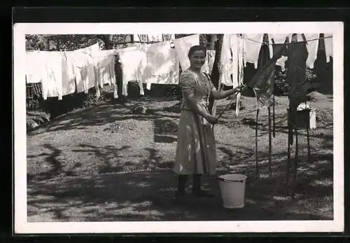 Foto-AK Junge Hausfrau mit Wäscheleine im Garten