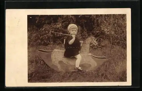 Foto-AK Mädchen sitzt mit ihrer Peitsche auf einem Schaukelpferd