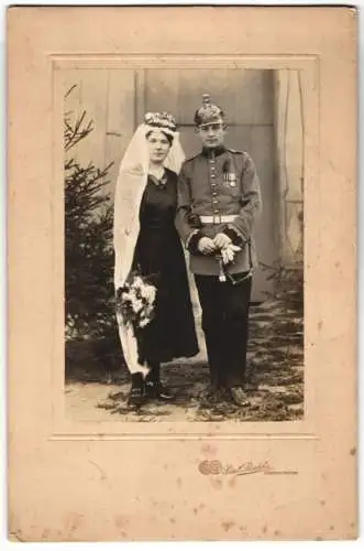 Fotografie Paul Peschke, Obernkirchen, Soldat in Artilerie Uniform Pickelhaube nebst seiner Braut, Kriegstrauung, Orden