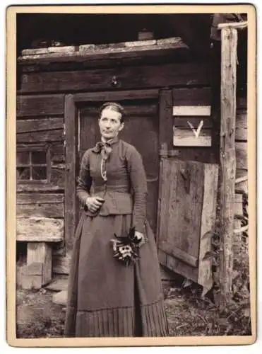 Fotografie unbekannter Fotograf und Ort, Dame im dunklen Kleid vor einer Holzhütte