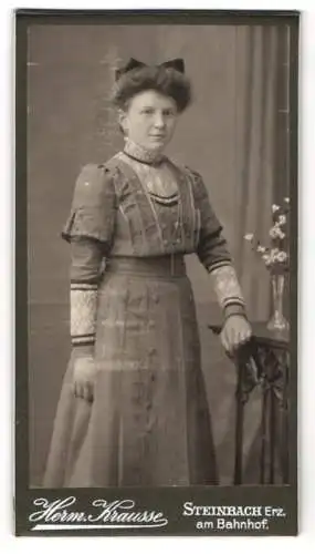 Fotografie H. Krausse, Steinbach Erz., am Bahnhof, Junge Frau im Kleid mit hohem Kragen und Schleife im Haar