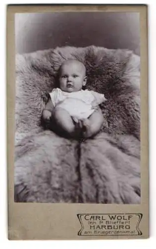 Fotografie Carl Wolf, Harburg, am Kriegerdenkmal, Porträt eines Babys auf einem Fell