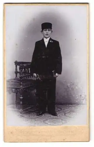 Fotografie Otto Petermann, Aachen, Kurhaus-Promenadenstrasse, Junge in feierlicher Kleidung neben geschnitztem Stuhl