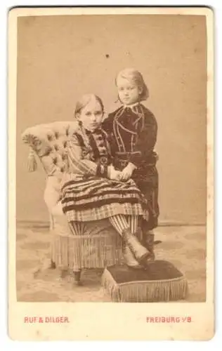 Fotografie Ruf & Dilger, Freiburg, Ludwigstrasse 2, Zwei Kinder in Sonntagskleidung auf elegantem Sessel