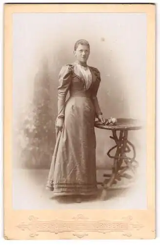 Fotografie Georg Schönau, Nürnberg, Bayreuther Strasse 20, Frau in elegantem Kleid neben Tisch mit Blume