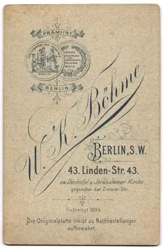 Fotografie U.K. Böhme, Berlin, Linden-Str. 43, Herr mit Buch stehend vor einem kunstvoll verzierten Schreibtisch.