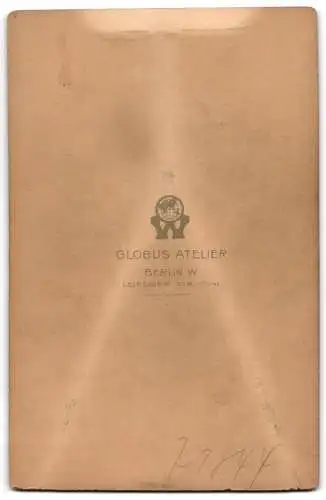 Fotografie Globus Atelier, Berlin, Leipziger Str. 132-135, Junger Mann im Anzug neben Tisch mit Hut und Buch