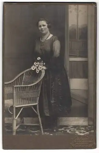 Fotografie Th. Eppler, Dresden, Hauptstrasse 24, Frau mit Blumenstrauss neben einem Korbstuhl