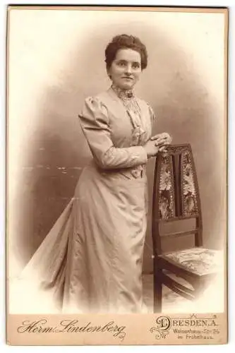 Fotografie Herm. Lindenberg, Dresden, Waisenhaus-Str. 24, Frau in elegantem Kleid an Stuhl gelehnt.