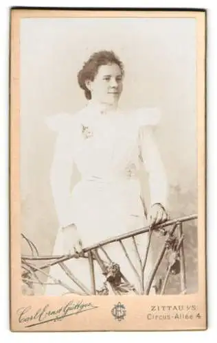 Fotografie Carl Ernst Güttges, Zittau, Circus-Allee 4, Junge Frau in weissem Kleid an dekorativem Geländer.