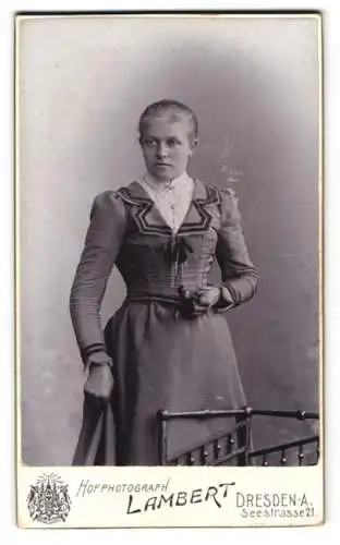 Fotografie Lambert, Dresden, Seestrasse 21, Junge Frau in elegantem Kleid neben Stuhl.