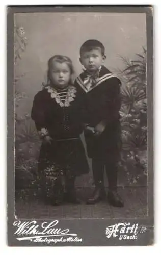 Fotografie Wilh. Lau, Hartha, Kinder in eleganter Kleidung vor einem botanischen Hintergrund