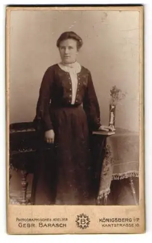 Fotografie Gebr. Barasch, Königsberg i/P, Kantstrasse 10, Junge Frau in dunklem Kleid neben Tisch mit Blumenvase