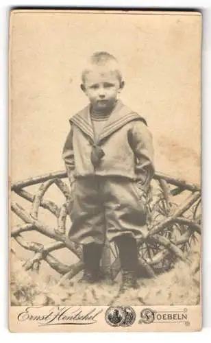 Fotografie Ernst Hentschel, Döbeln, Bahnhofstrasse 6, Junge im Matrosenanzug vor rustikalem Zaun