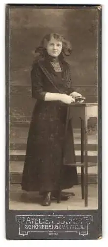 Fotografie A. Weiss & Co., Berlin, Hauptstrasse 11, Frau in elegantem Kleid an einem Tisch lehnend