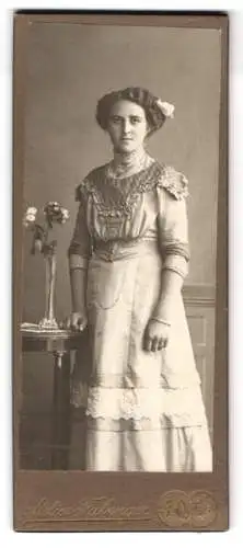 Fotografie Albert Fabinger, Werdau i.S., Junge Frau im eleganten Kleid mit Blumenarrangement