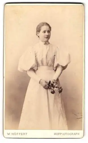 Fotografie W. Höffert, Berlin, Unter den Linden 24, Junge Frau im eleganten Kleid mit Blumenstrauss, 1894