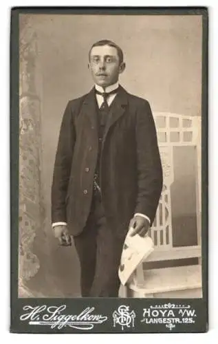 Fotografie H. Siggelkow, Hoya, Lange Str. 125, Porträt eines eleganten jungen Mannes mit Papier in der Hand