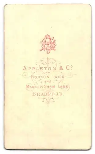 Fotografie Appleton & Co., Bradford, Horton Lane & Manningham Lane, Junge im Anzug neben Tisch