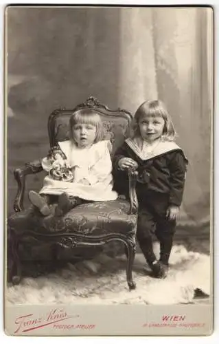 Fotografie Franz Knes, Wien, Landstrasse Hauptstrasse 2, Zwei Kinder posieren auf elegantem Stuhl