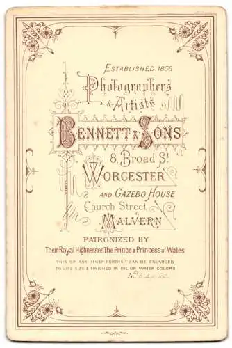 Fotografie J. Bennett & Sons, Worcester, Broad Street 8, Kleinkind in weissem Kleid vor Fellhintergrund