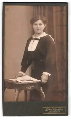 Fotografie Alfred Schwiebus, Leisnig, Frau steht an einem Tisch mit einem Buch