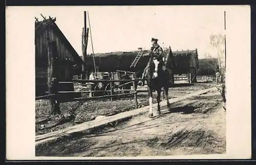 Foto-AK Golowinzy, Soldat auf Pferd vor Bauernhäusern