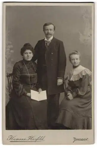 Fotografie Heimann Herzfeld, Dresden, Altmarkt, Porträt einer sitzenden Frau mit Buch, einem stehenden Mann und einem si