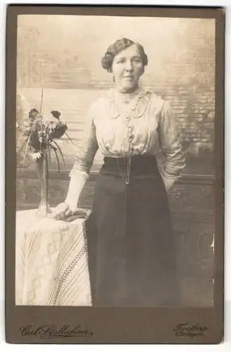 Fotografie Carl Stallechner, Trostberg, gegenüber der Stadtpfarrkirche, Frau steht neben einem Tisch mit Blumenstrauss