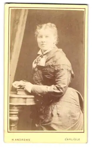 Fotografie H. Andrews, Carlisle, Sheffield Street 46, Frau in elegantem Kleid an Tisch gelehnt