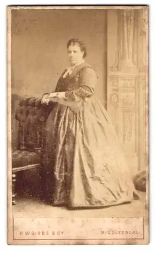 Fotografie R.W. Gibbs & Co., Middlesboro, Wilson Street 20, Frau in elegantem Kleid neben Stuhl