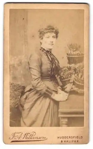 Fotografie F.A. Wilkinson, Huddersfield, Byram Arcade, Frau in elegantem Kleid neben Pflanzenarrangement