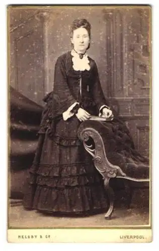 Fotografie Helsby & Co, Liverpool, Church Street 34, Dame in elegantem Kleid neben einem Polstersessel