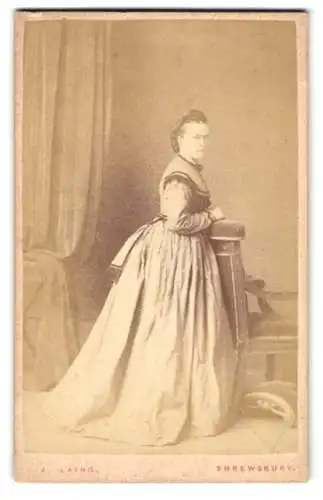 Fotografie J. Laing, Shrewsbury, Castle Street, Frau im eleganten Kleid steht neben einem Stuhl