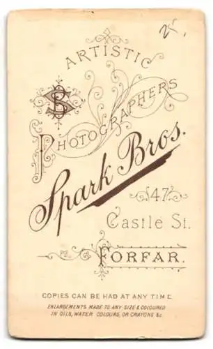 Fotografie Spark Bros., Forfar, Castle St. 47, Kleinkind in einem weissen Kleid auf einem gepolsterten Stuhl