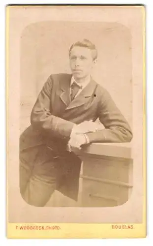 Fotografie F. Woodcock, Douglas / Isle of Man, Eleganter Mann lehnt an einem Tisch