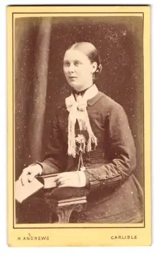 Fotografie H. Andrews, Carlisle, Sheffield Street 46, Dame in elegantem Kleid mit Buch