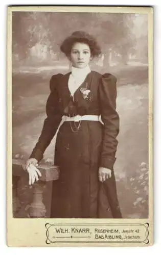 Fotografie Wilh. Knarr, Rosenheim, Innstrasse 42, Elegante junge Frau in dunklem Kleid mit Blumenbrosche