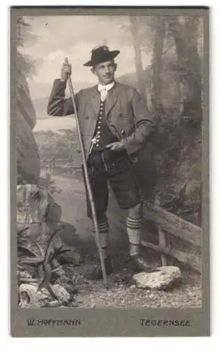 Fotografie W. Hoffmann, Tegernsee, Junger Mann in Tracht mit einem Wanderstab, Lederhose