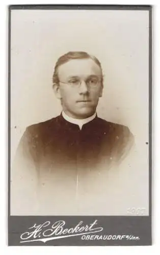 Fotografie H. Beckert, Oberaudorf a. Inn, Junger Geistlicher mit einer Brille und Kollar