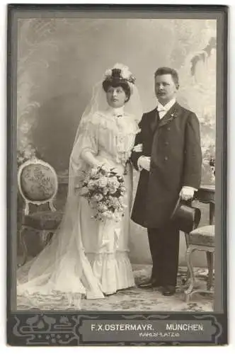 Fotografie F. X. Ostermayr, München, Karlsplatz 6, Ein Hochzeitspaar in Brautkleid und Anzug in einem Studio, Zylinder