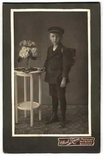 Fotografie Albert Kaune, Misburg, Bahnhofstrasse, Junge in Schuluniform neben einem Tisch mit Blumenstrauss