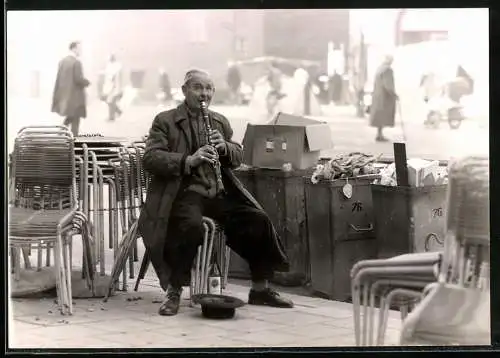 Fotografie F. Pikola, München-Schwabing, Ansicht München, Strassenmusiker spielt Blasinstrument neben Mülltonnen